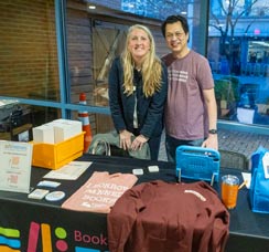 White man and woman standing behind display table with FOAL merchandise