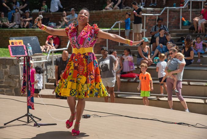 Black women in cultural dress smiling and dancing on stage