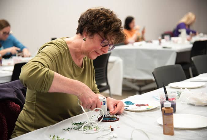Woman hot gluing crafts on a table